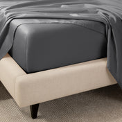 A close-up of the corner of a bed with a fitted sheet and matching flat sheet.