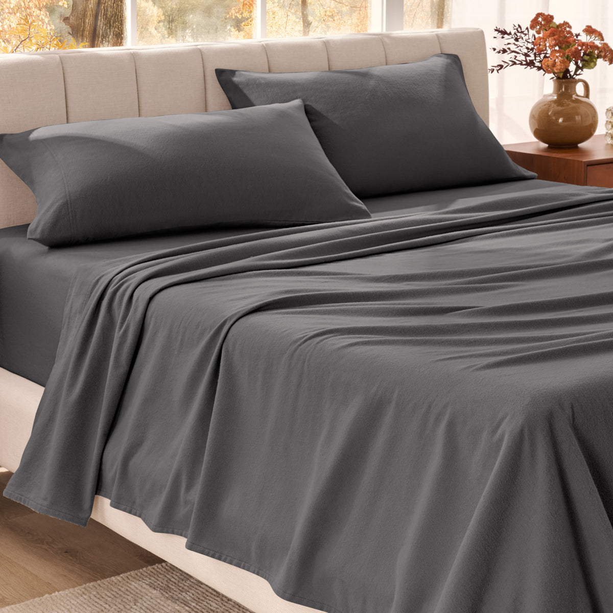 Bed sheets on a neatly made bed in a bright bedroom with large windows.