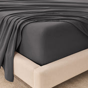 Fitted sheet and top sheet on a mattress with a beige bed frame