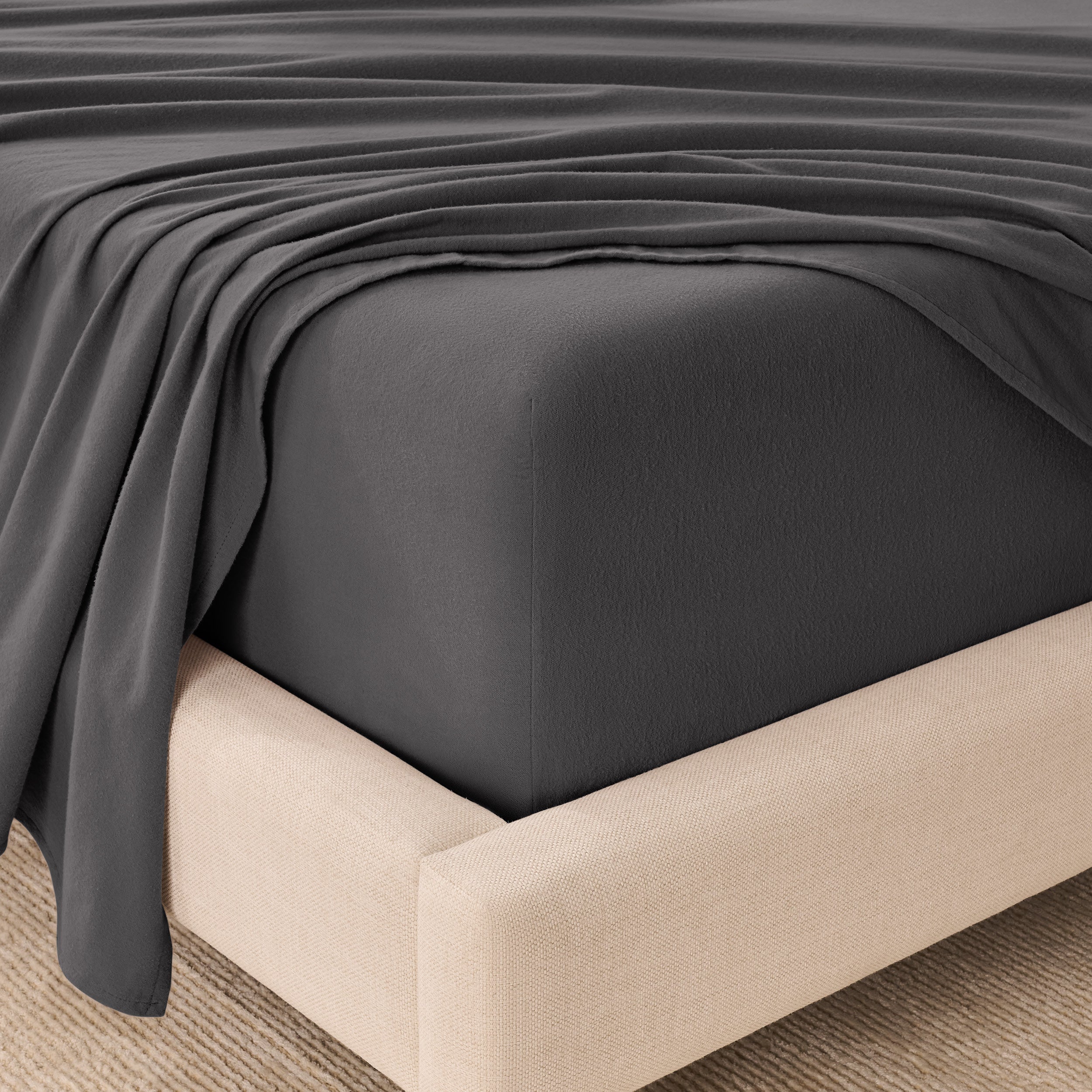 Fitted sheet and top sheet on a mattress with a beige bed frame
