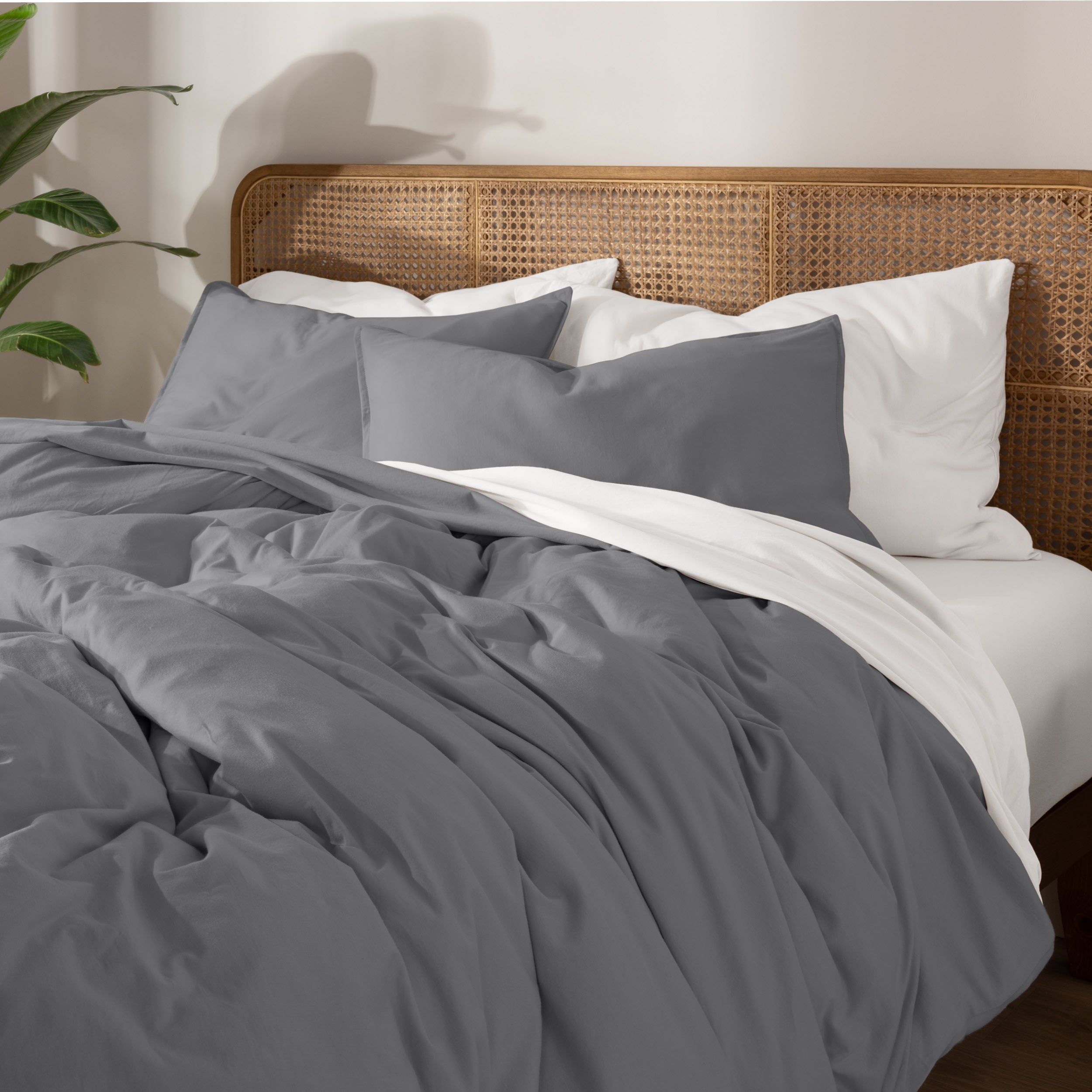 Bedding set on a bed with a wicker nightstand and lamp in a bedroom setting.