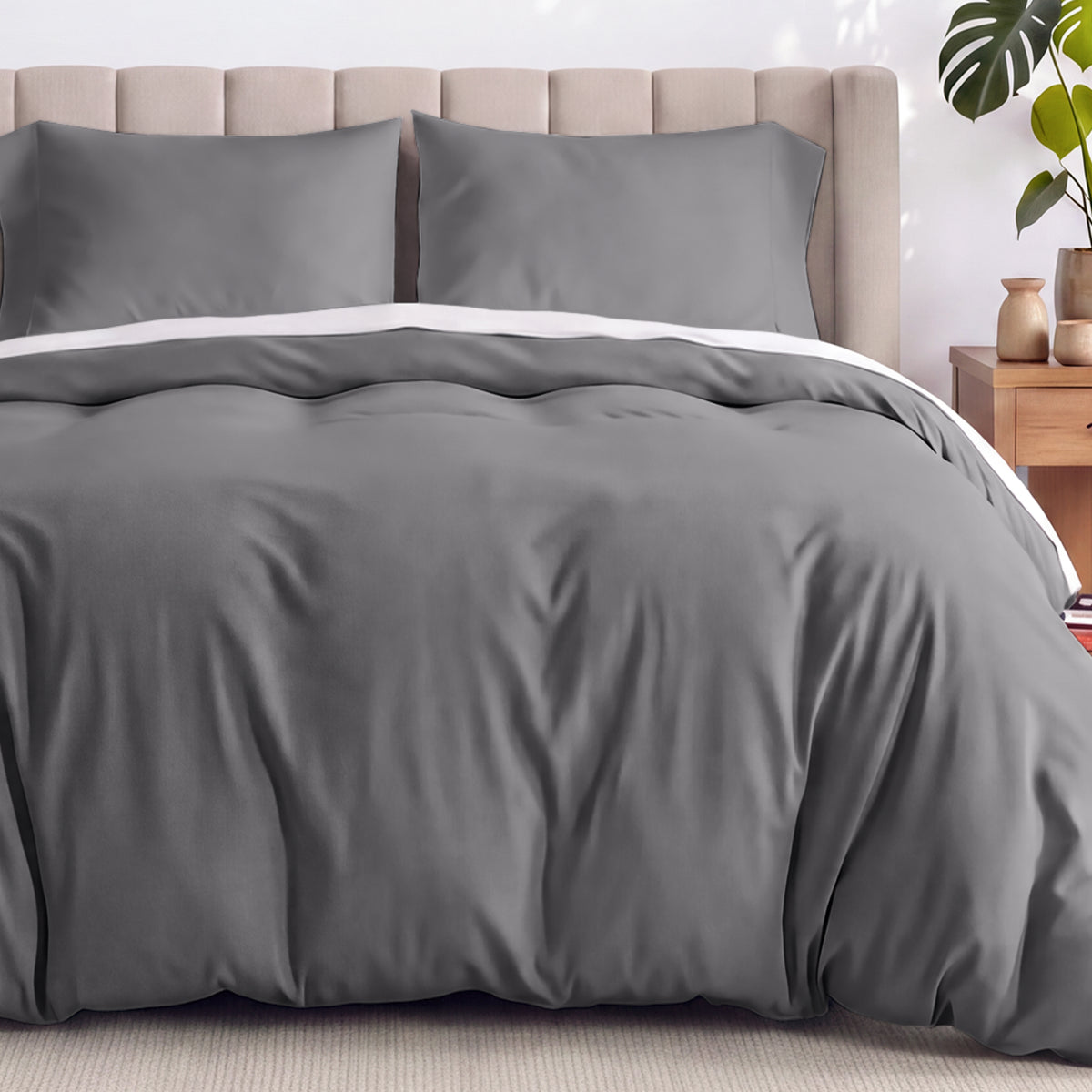 Gray duvet set on a bed with a wicker headboard and plants in the background.