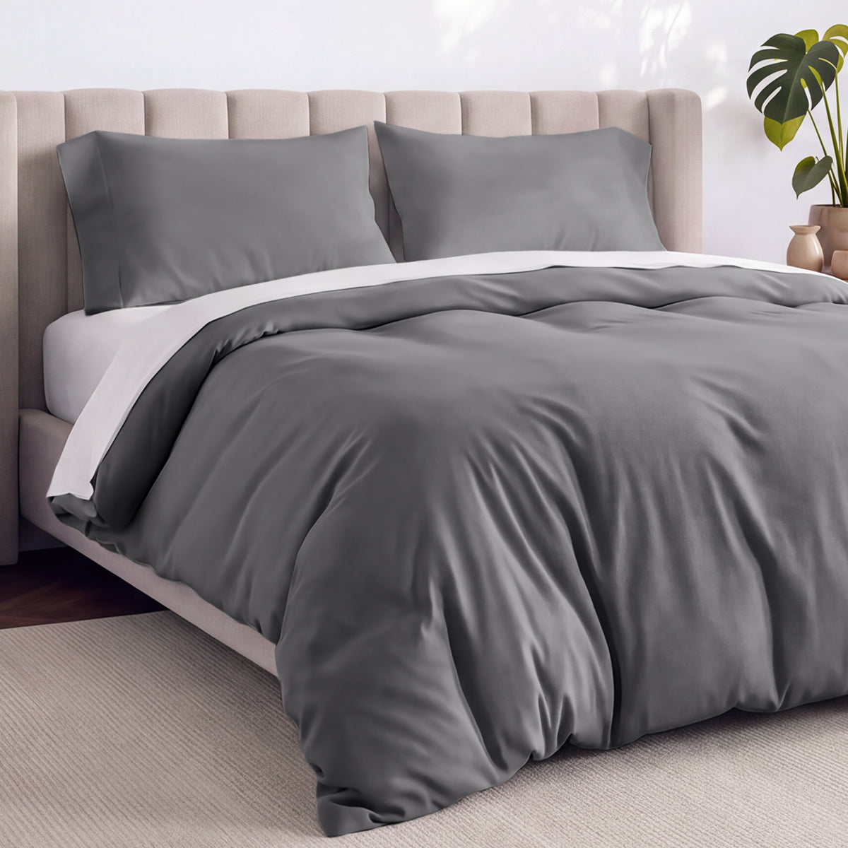A neatly made bed with gray bedding, white pillows, and a wooden headboard. 