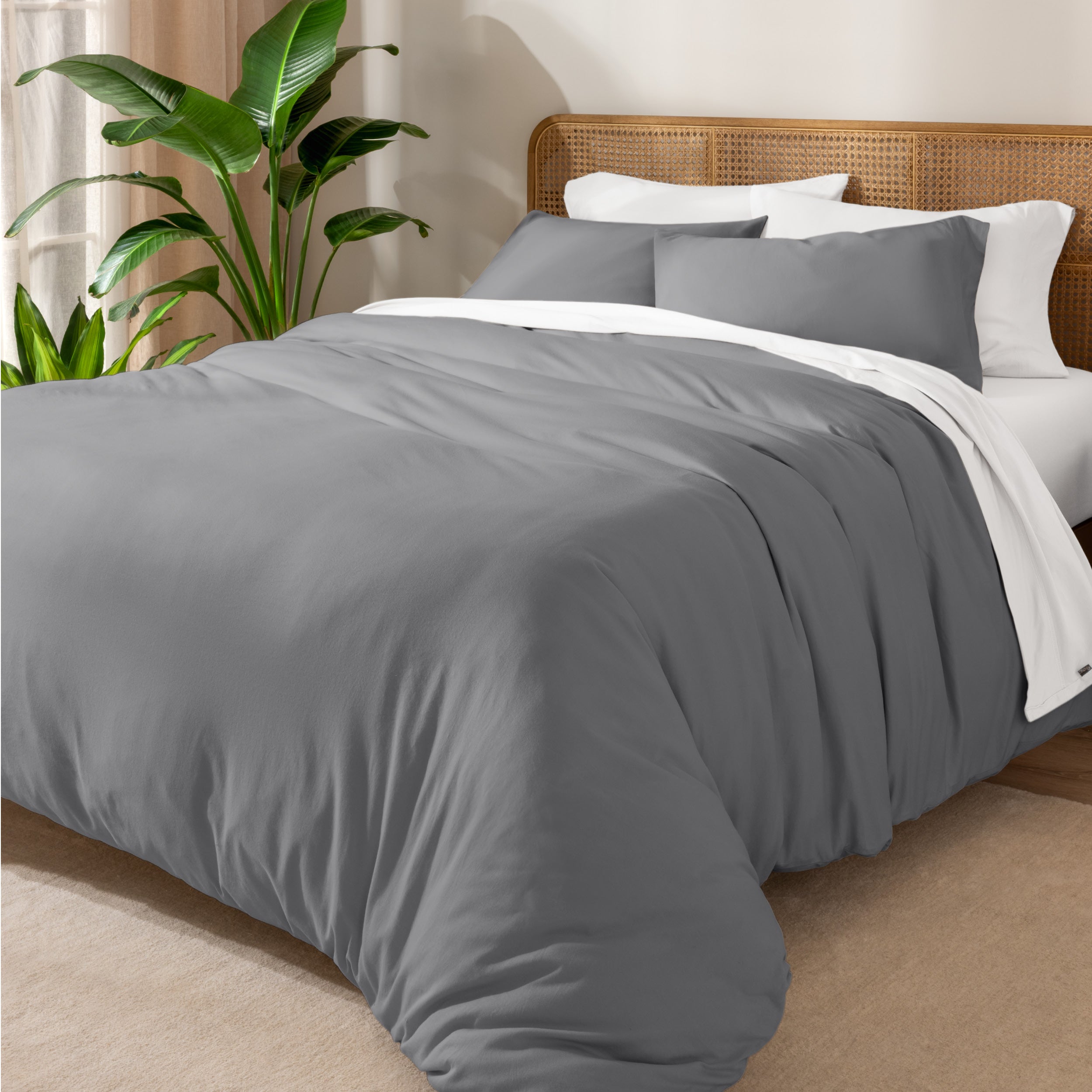 A cozy bed dressed in white sheets and pillows, complemented by an organic cotton jersey duvet cover set.