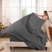 Woman putting a sheet set on a bed in a bright bedroom.