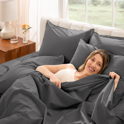 Woman lying in bed with percale bedding in a bright bedroom