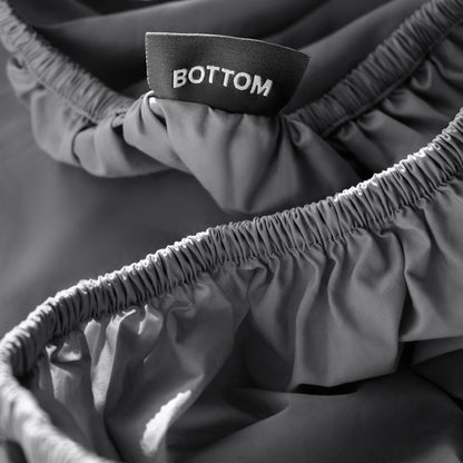 Close-up of a fitted sheet with a black fabric brand label reading BOTTOM.