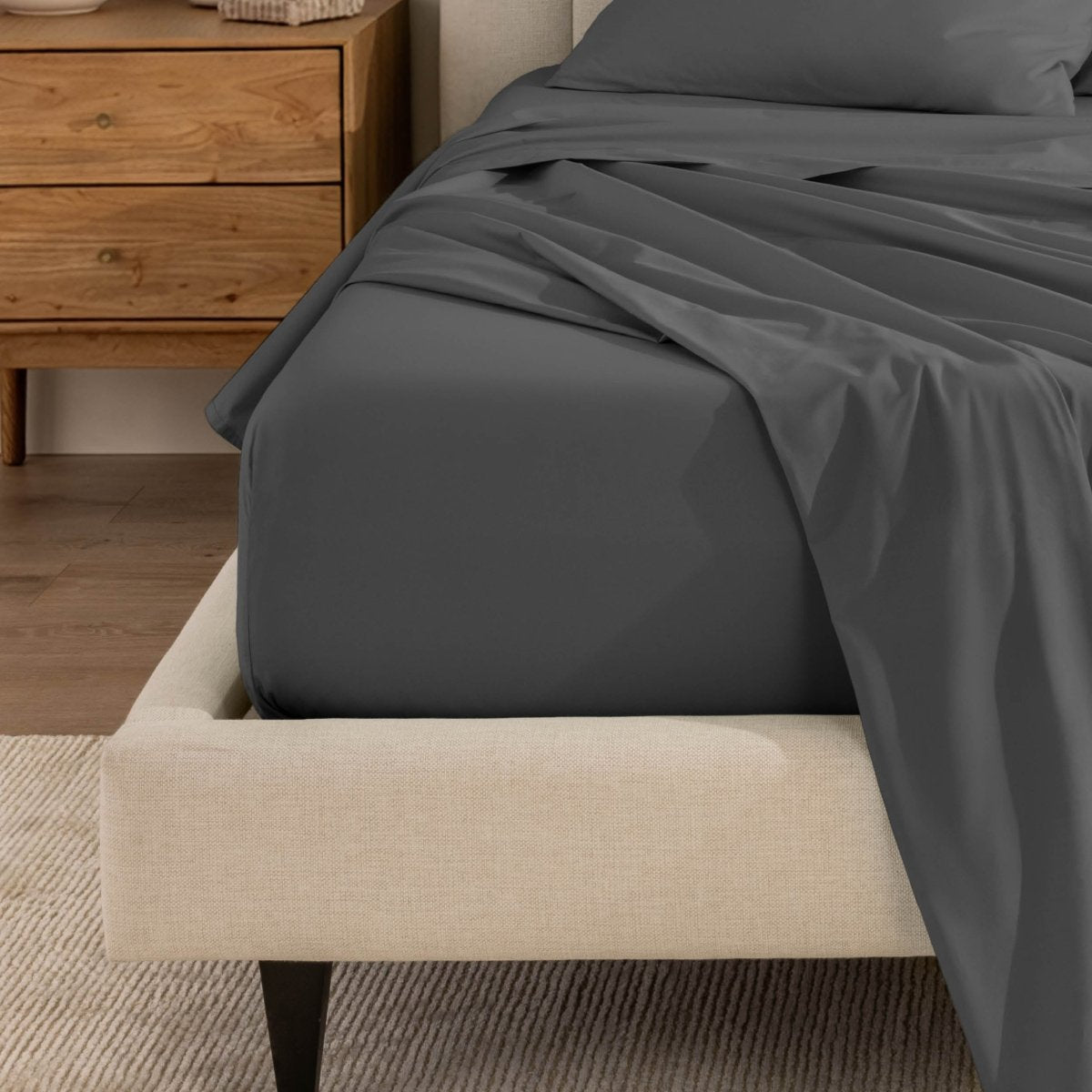 Top sheet and a matching fitted sheet on a bed with a beige bed frame