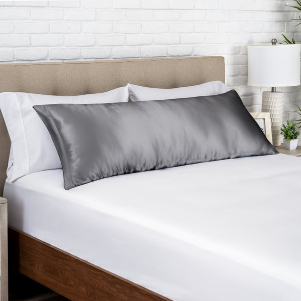 Gray satin pillow on a bed with white bedding and a wooden headboard.