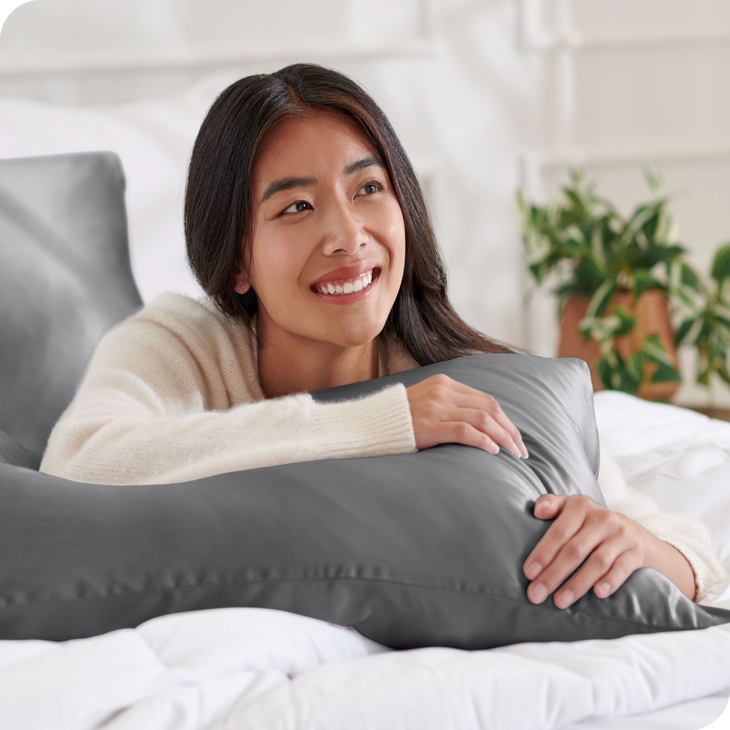 A woman is resting on a satin pillowcase covered pillow