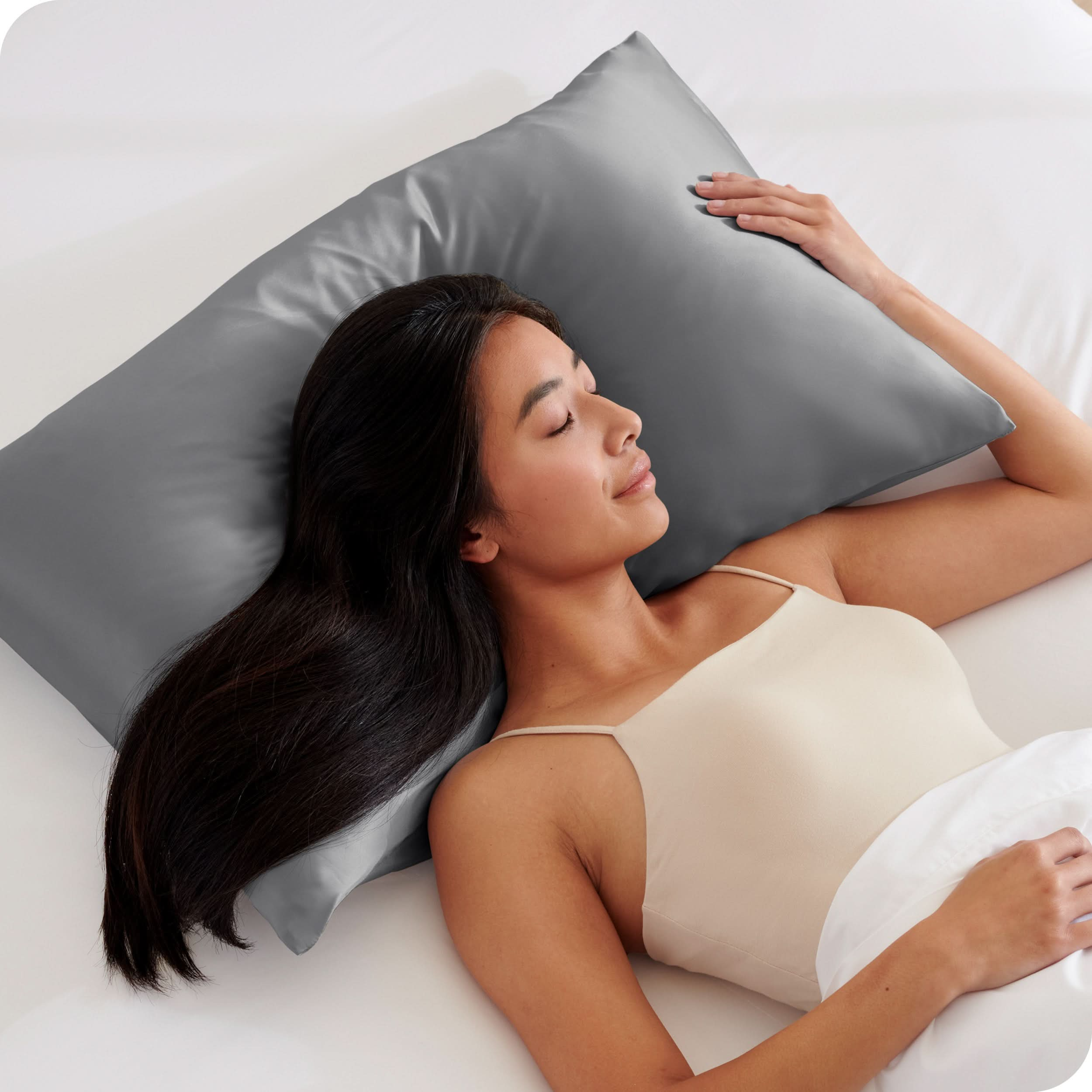 A woman is sleeping on a pillow with a satin pillowcase