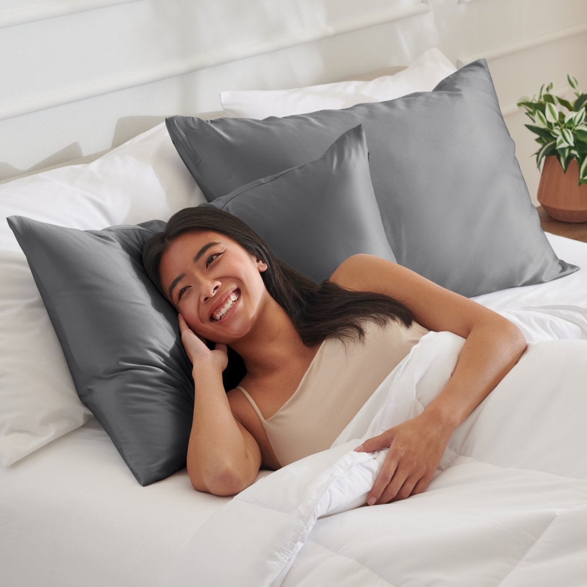 Woman lying on a bed with satin pillows and white bedding