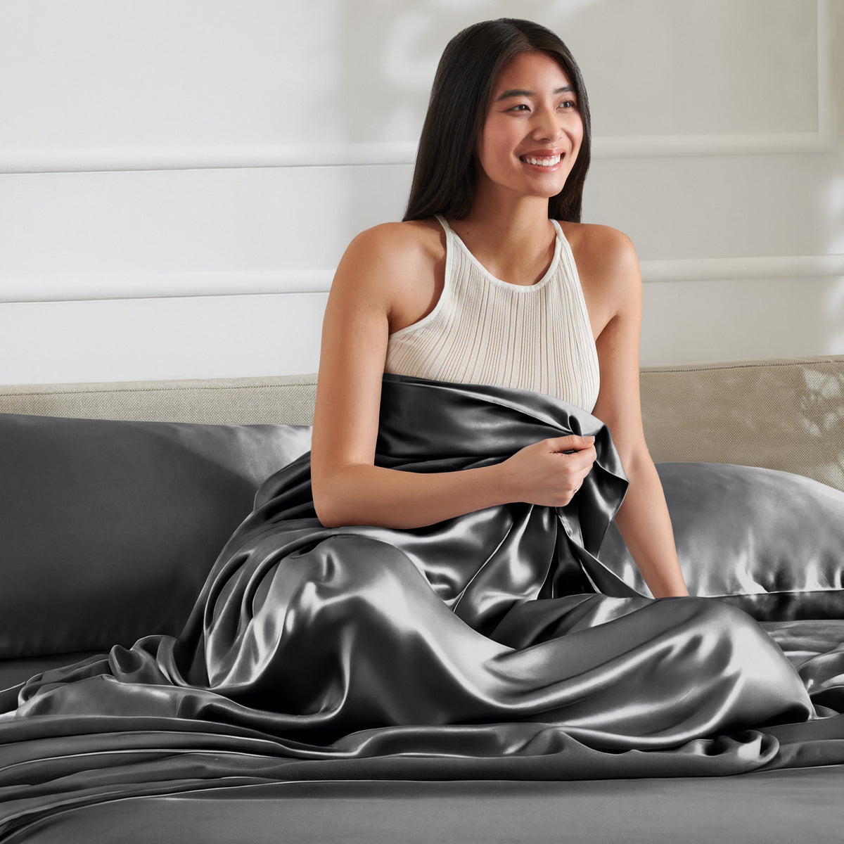 Woman sitting on a bed with satin sheets