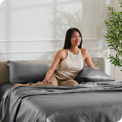 A woman is resting on a bed make with satin sheets