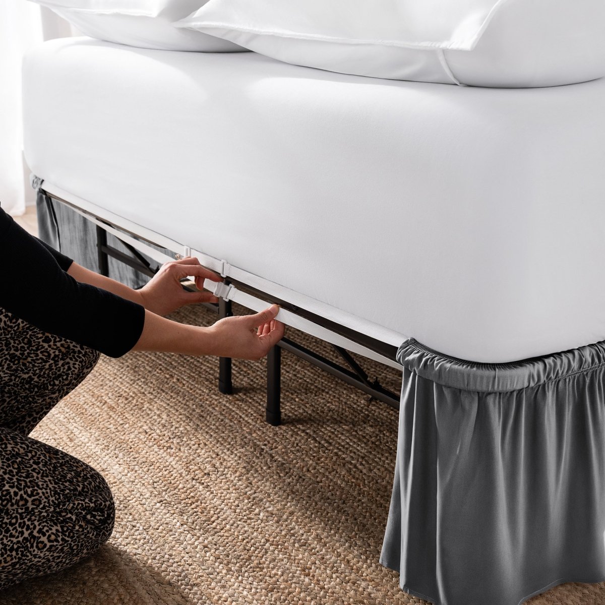 Adjustable bed skirt on a bed showing the elastic strap.
