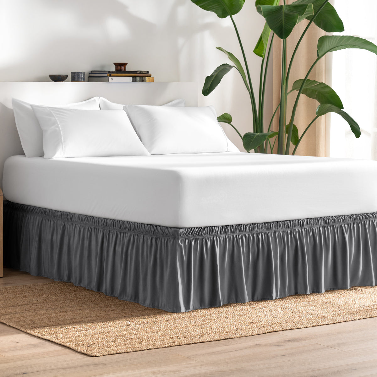 Bed with bed skirt, white bedding, and a plant in a room.