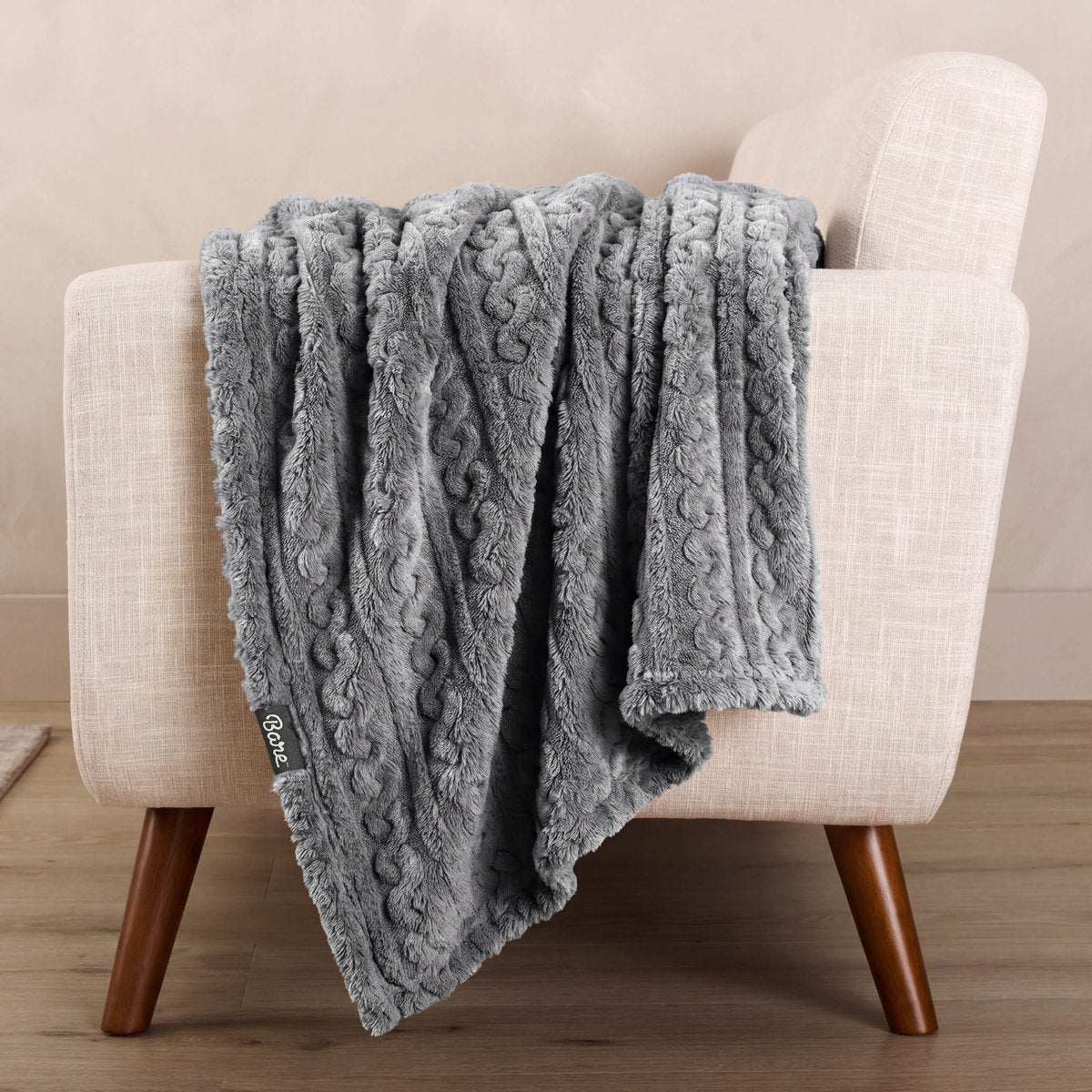 Cable knit blanket draped over the arm of a chair