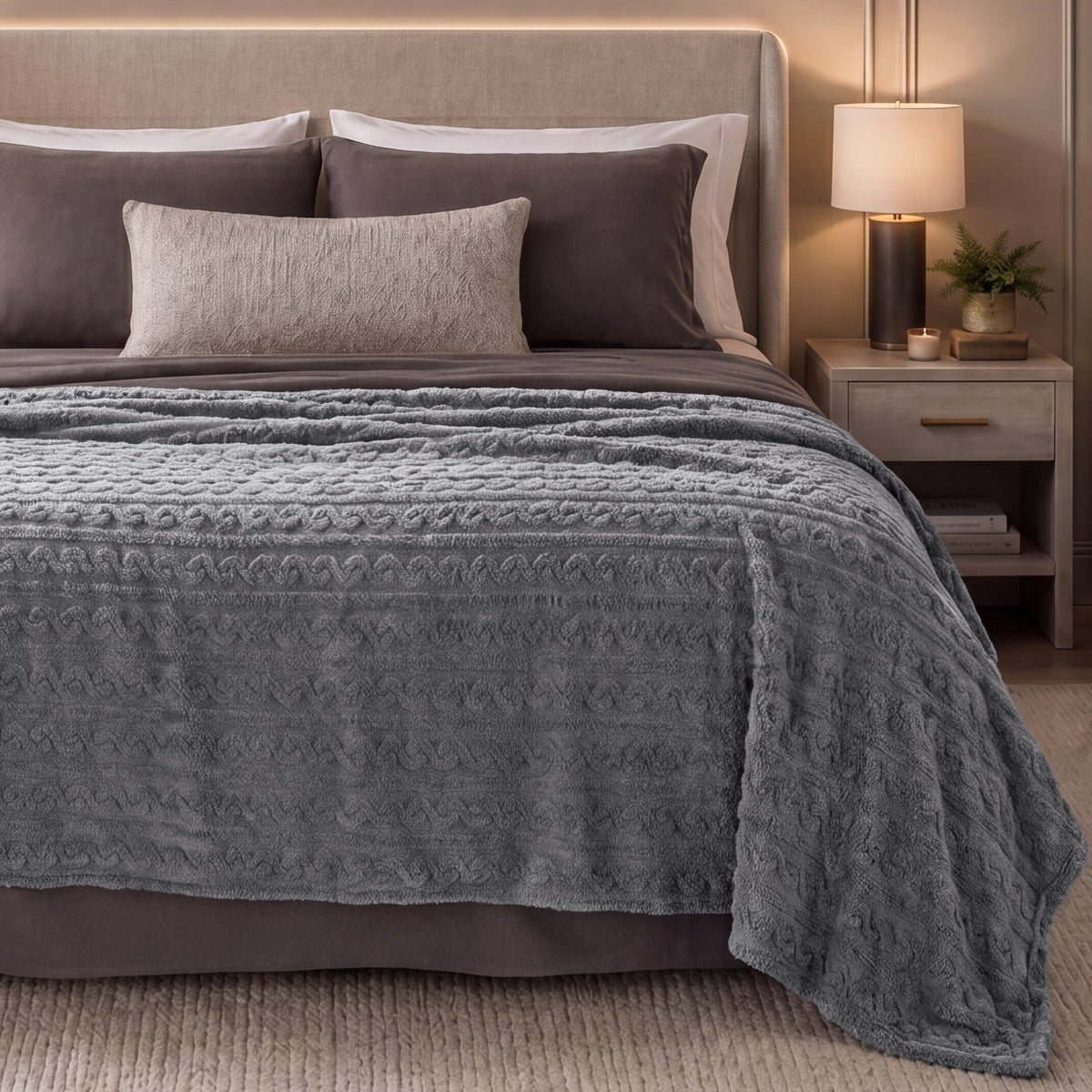 Bed with grey textured blanket in a bedroom setting.