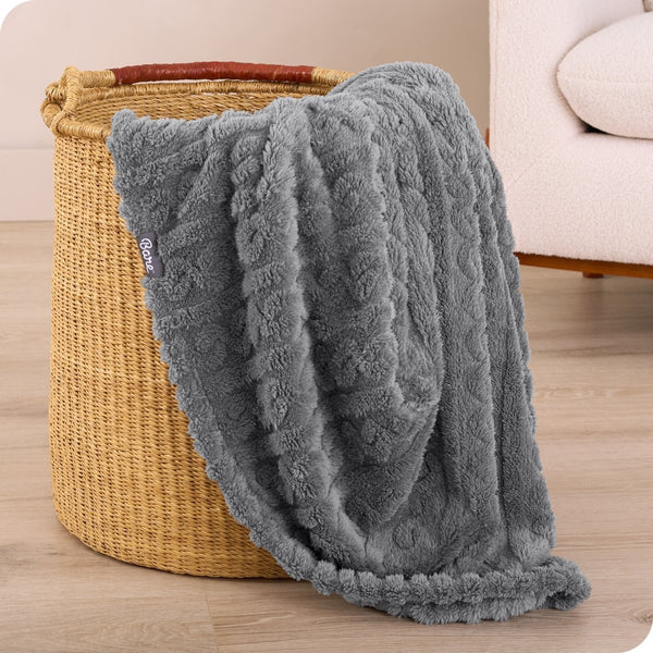 A sherpa blanket is hanging over the edge of a woven hamper