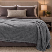Bed with gray blanket and pillows in a bedroom setting
