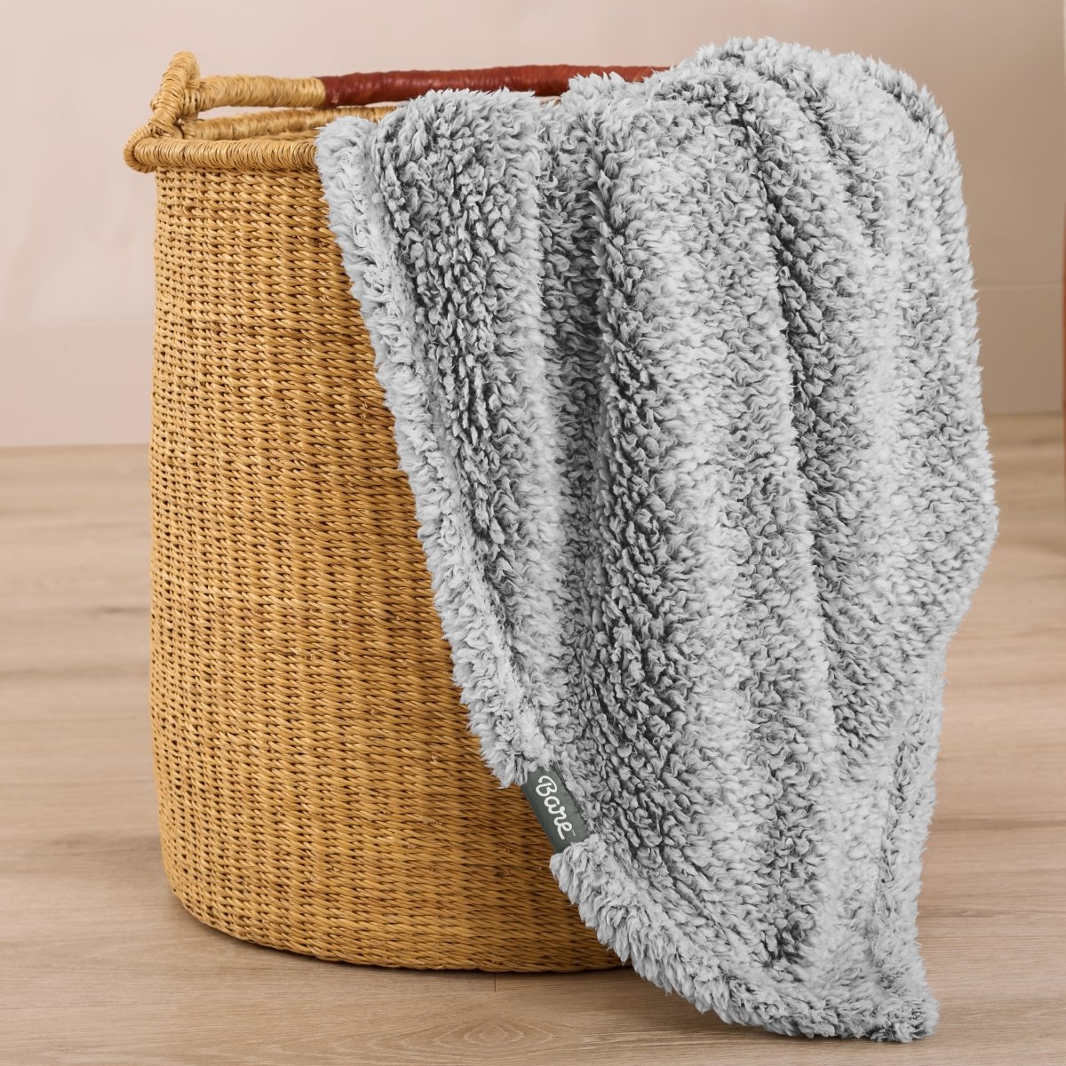 Textured blanket draped over a wicker basket on a wooden surface