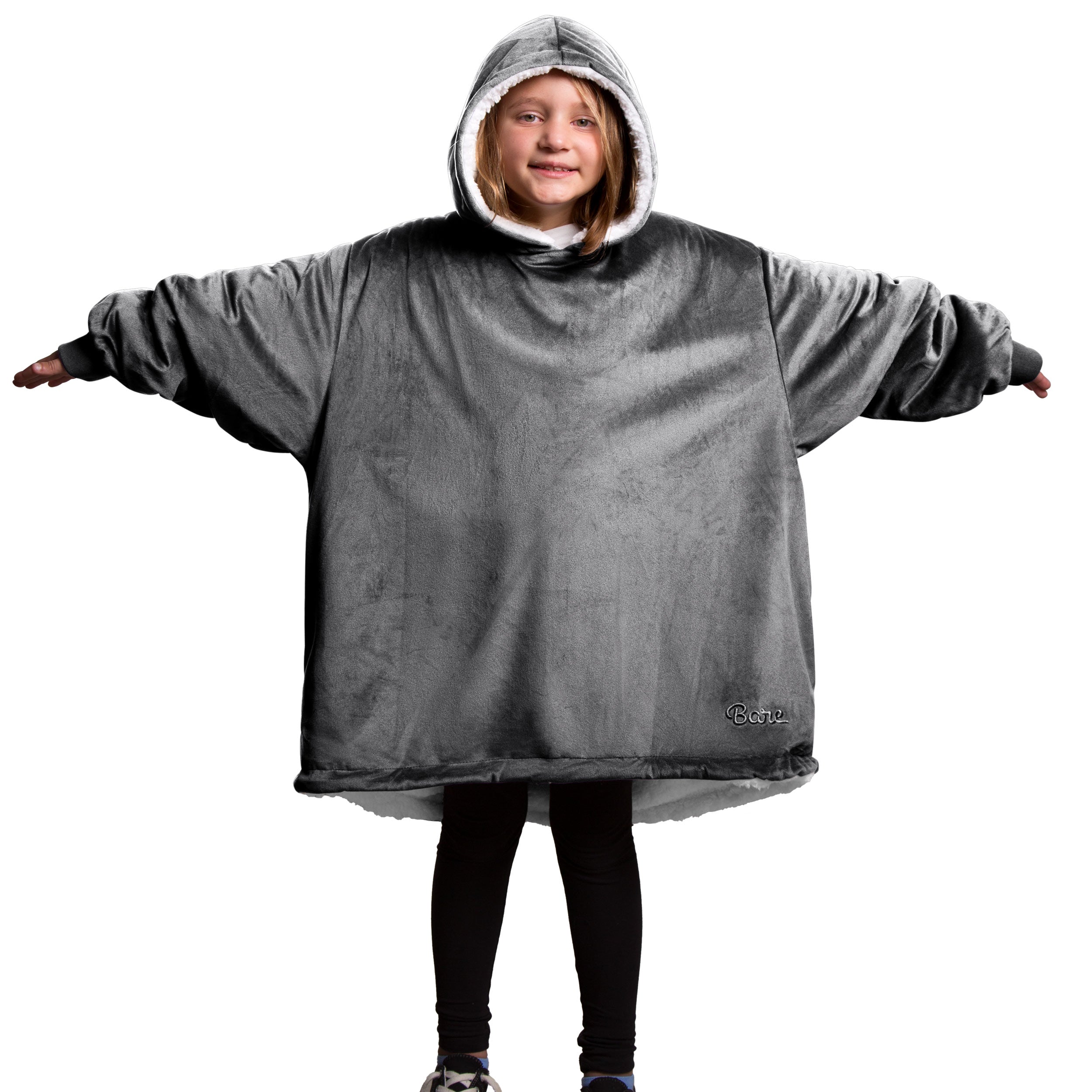 A child is wearing a sherpa wearable blanket and is standing with her arms stretched out.