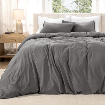 Washed duvet set on a bed in a bright bedroom with a lamp and window.