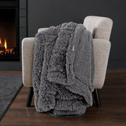 Sherpa blanket draped over an armchair in front of a fireplace.