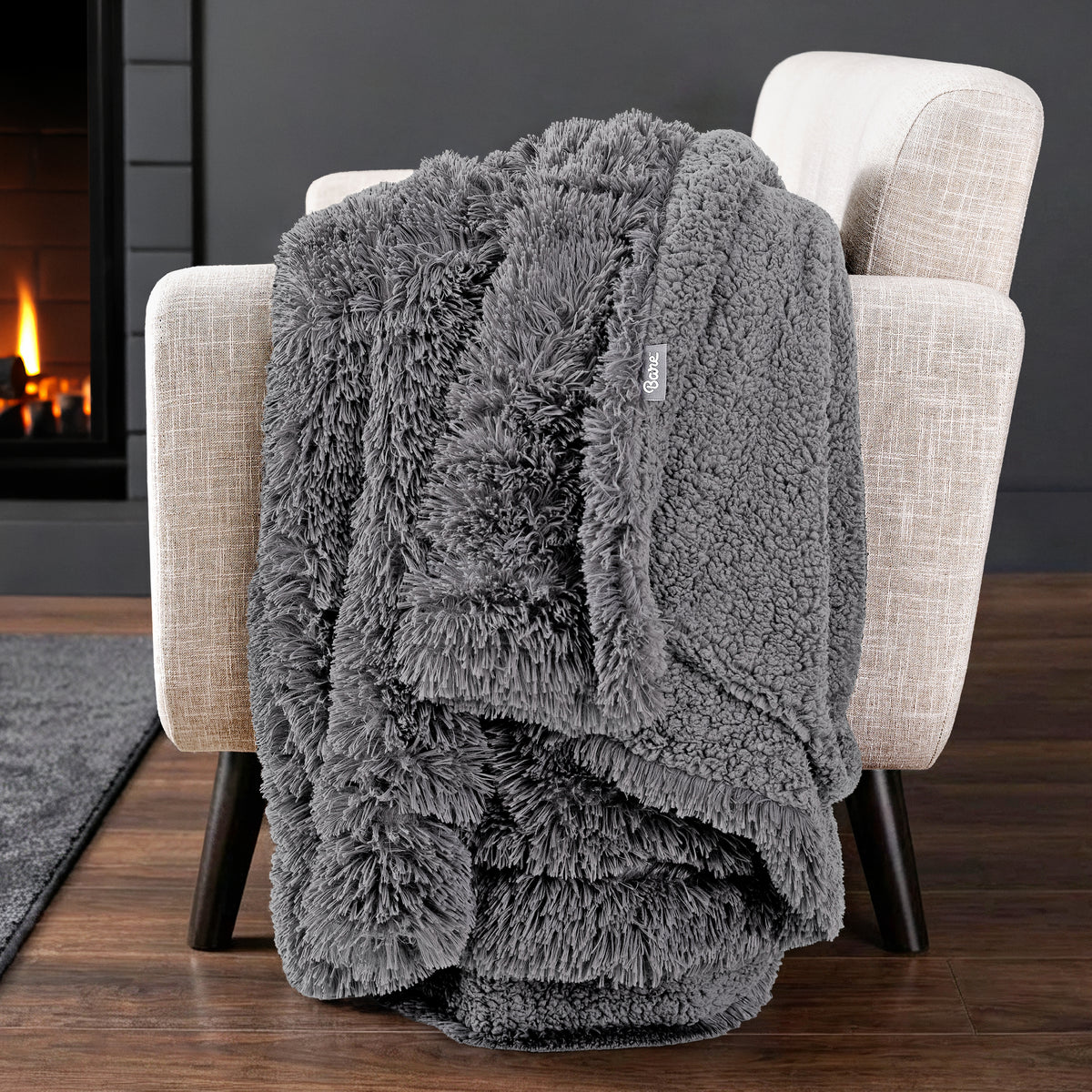 Sherpa blanket draped over an armchair in front of a fireplace.