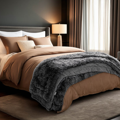 A shaggy faux fur blanket at the end of a bed