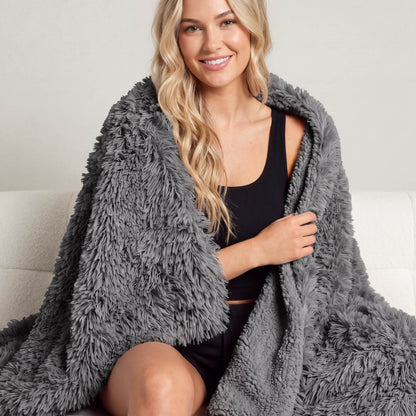 A woman sitting with a shaggy blanket wrapped around her