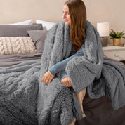 Fluffy blanket draped over a woman sitting on the end of a bed