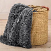 A blanket hanging over the edge of a wicker basket