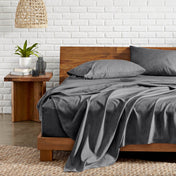Bedroom with wooden bed, nightstand, and white brick wall.