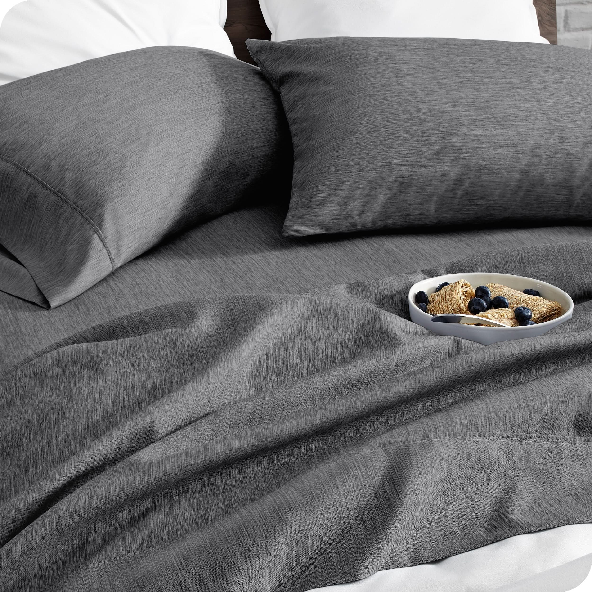 A bed made with sheets. A cereal bowl is on the sheets.