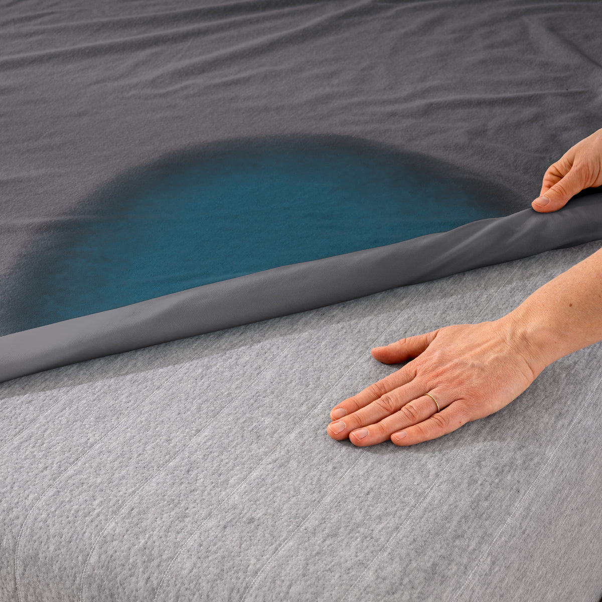 A bed with a grey mattress protector on it