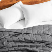 Close up of a weighted blanket on a bed next to pillows