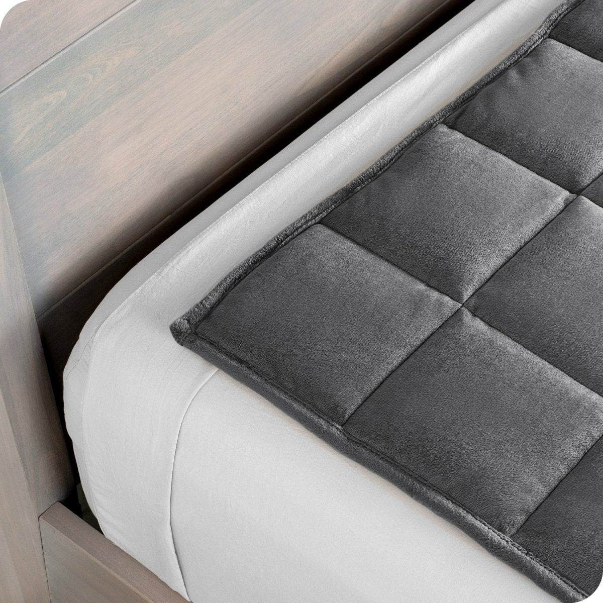 Close up of a weighted blanket on top of a bed made with white sheets