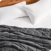 Close up of a weighted blanket on a bed next to pillows