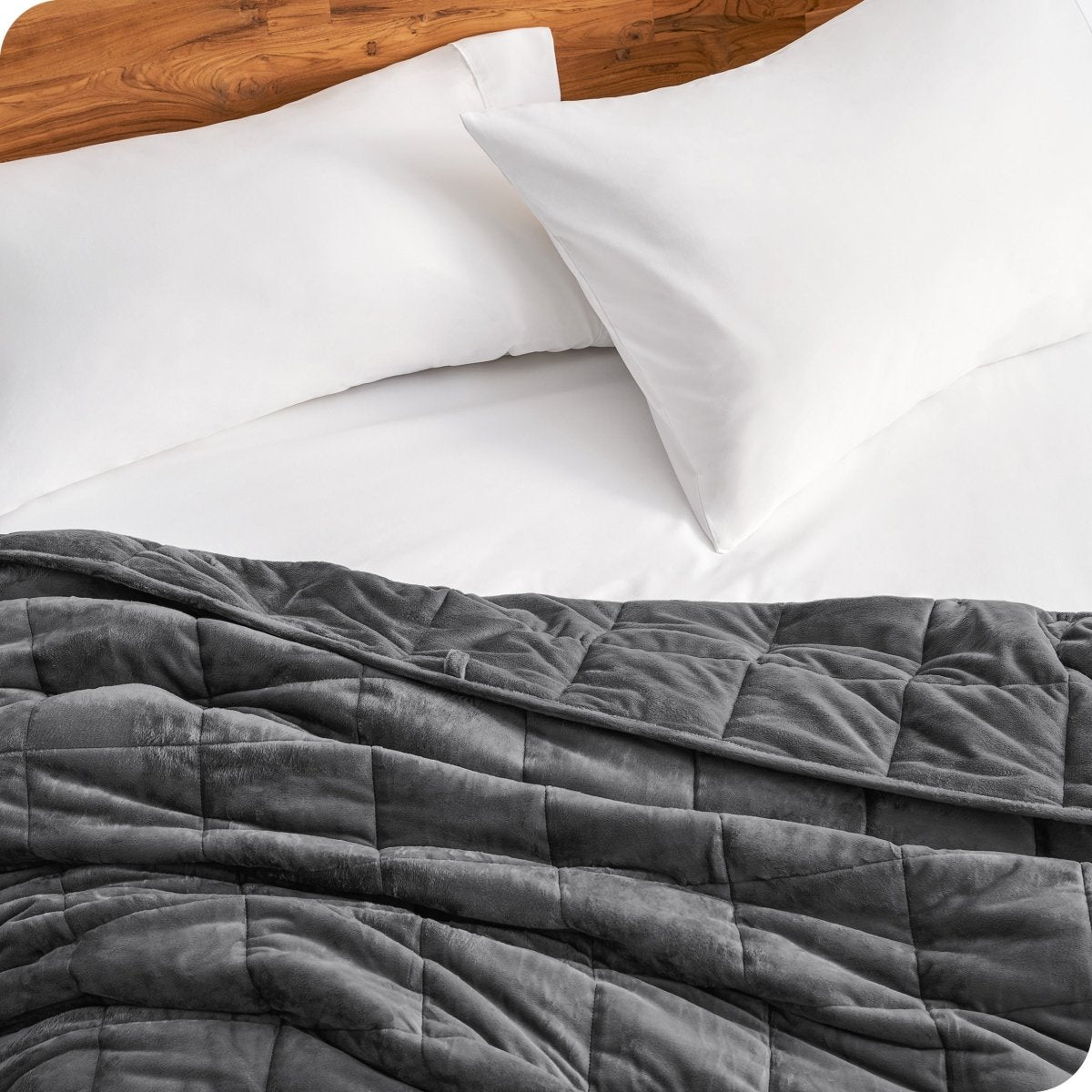 Close up of a weighted blanket on a bed next to pillows