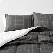 A comforter set on a bed against a white wall.