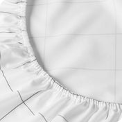 Close-up of a white fitted sheet with a subtle gray grid pattern