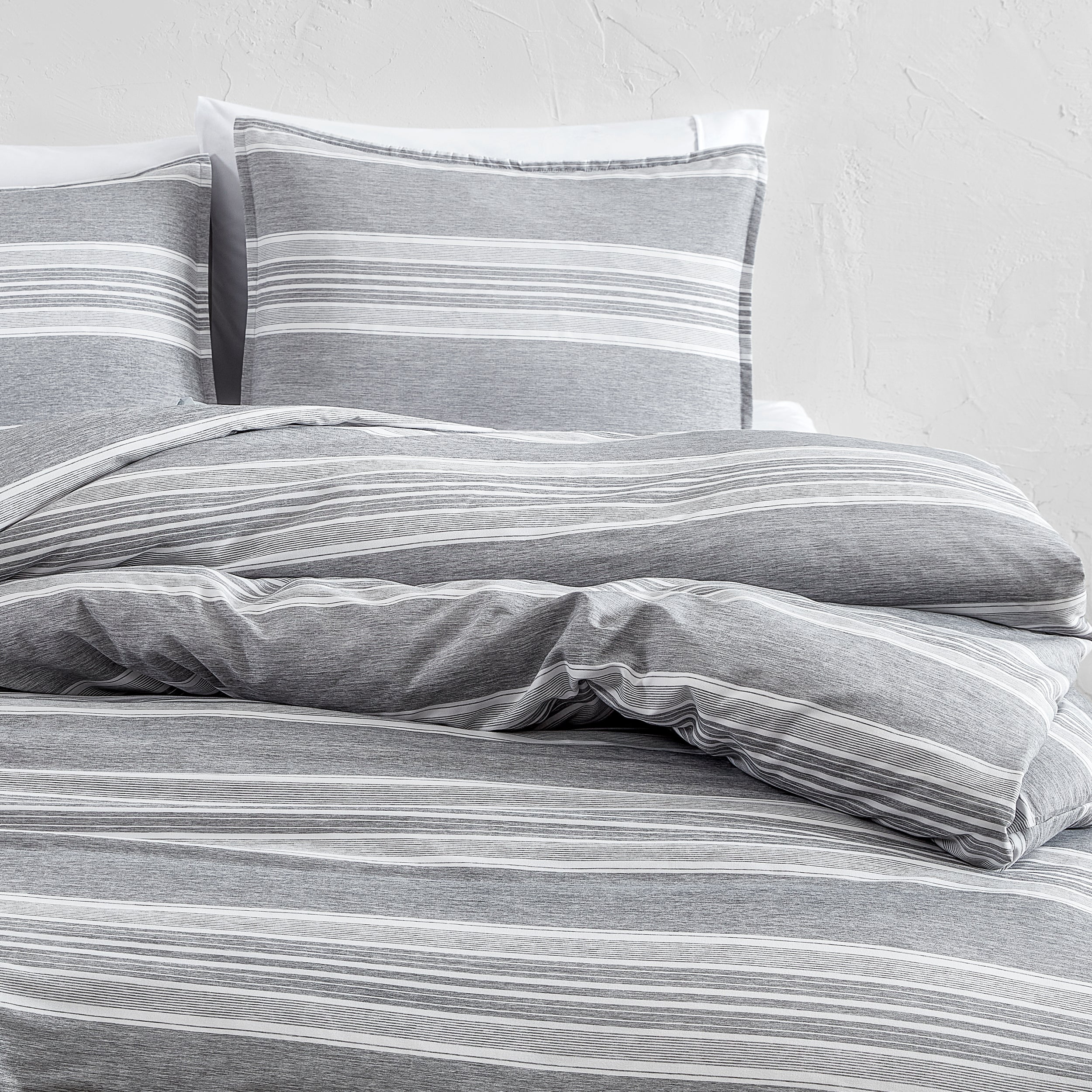 Gray striped bedding set on a bed with a white background