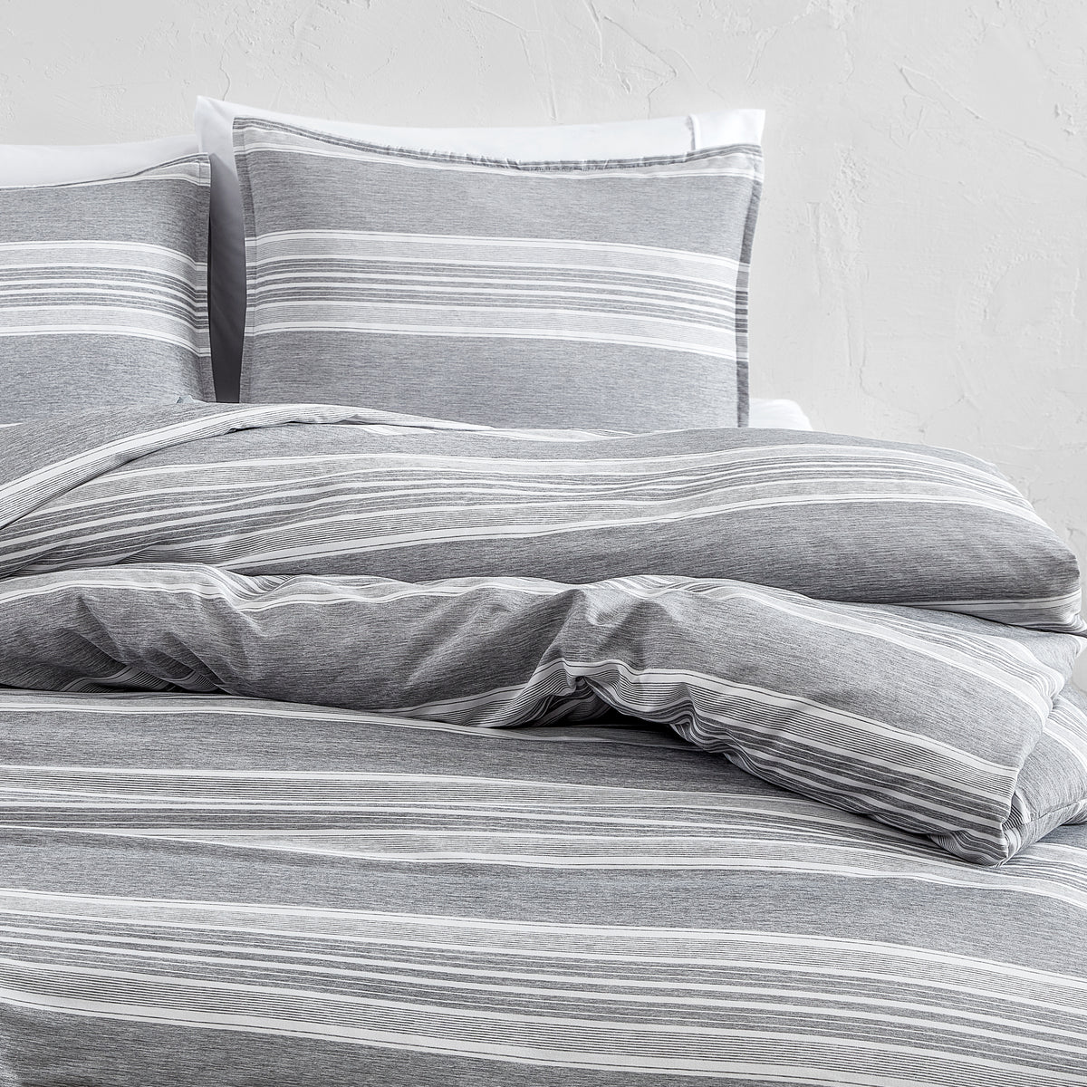 Gray striped bedding set on a bed with a white background
