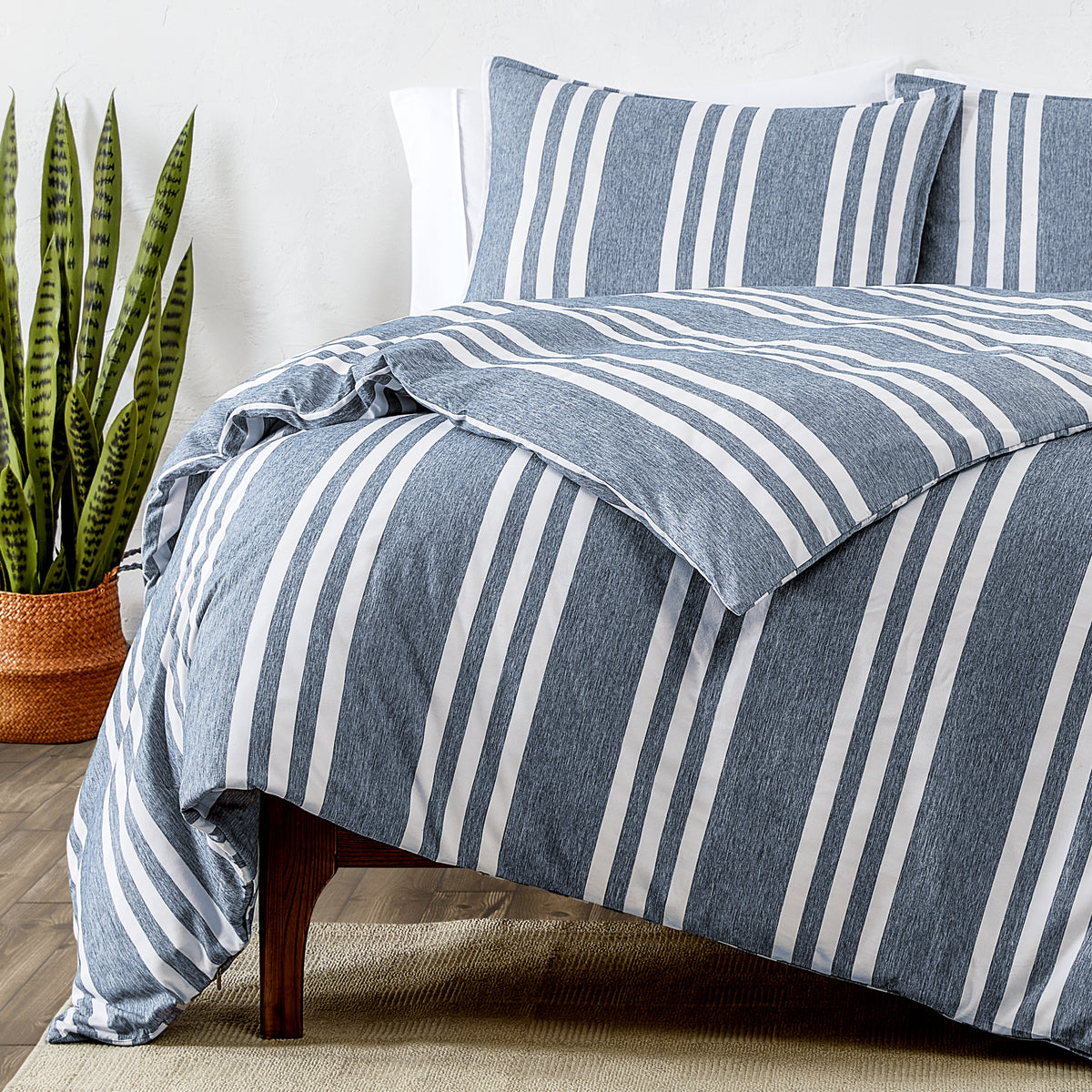 Blue and white striped bedding set on a bed with a plant in the background