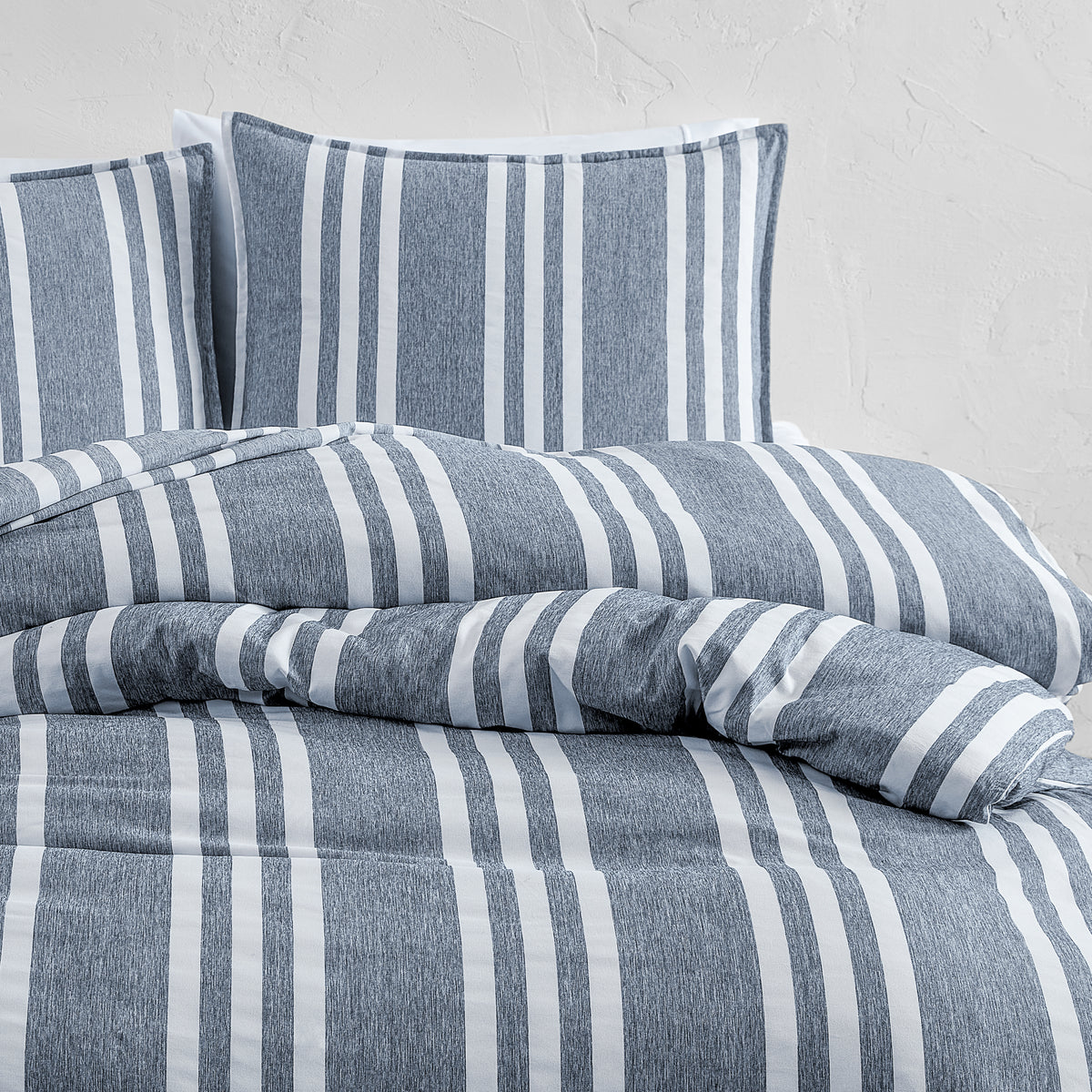 Blue and white striped bedding set on a bed with a light gray background