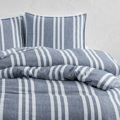 Blue and white striped bedding set on a bed with a light gray background