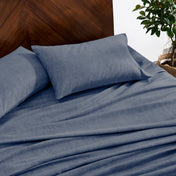 Indigo bedding set on a bed with a wooden headboard and plant in the background