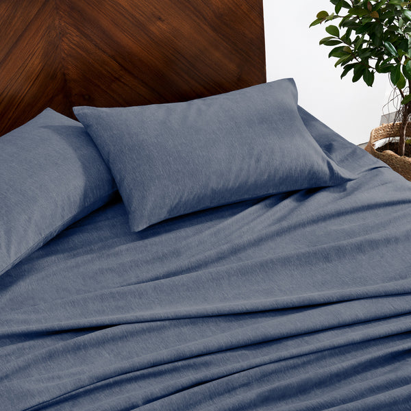 Indigo bedding set on a bed with a wooden headboard and plant in the background