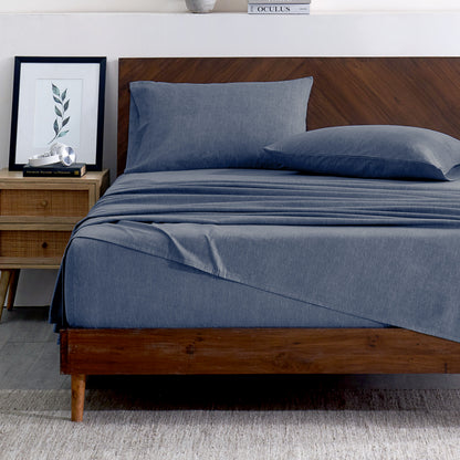 Indigo bedding set on a bed with a wooden headboard and plant in the background